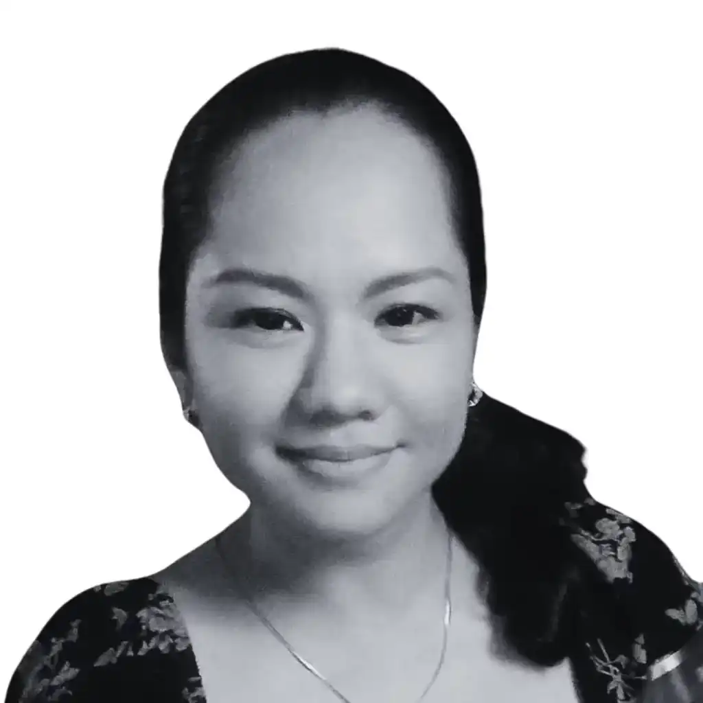 A grayscale portrait of a person with long, dark hair tied back. The individual is smiling, wearing earrings, a necklace, and a dark, patterned top that exudes an organic elegance. The background is plain white. Opdee Digital Marketing