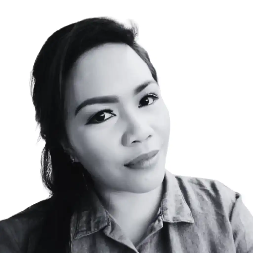 Black and white close-up photo of a woman with long hair and a slight smile. She is wearing a collared shirt and looking directly at the camera against a plain background, embodying an organic charm that draws viewers in. Opdee Digital Marketing