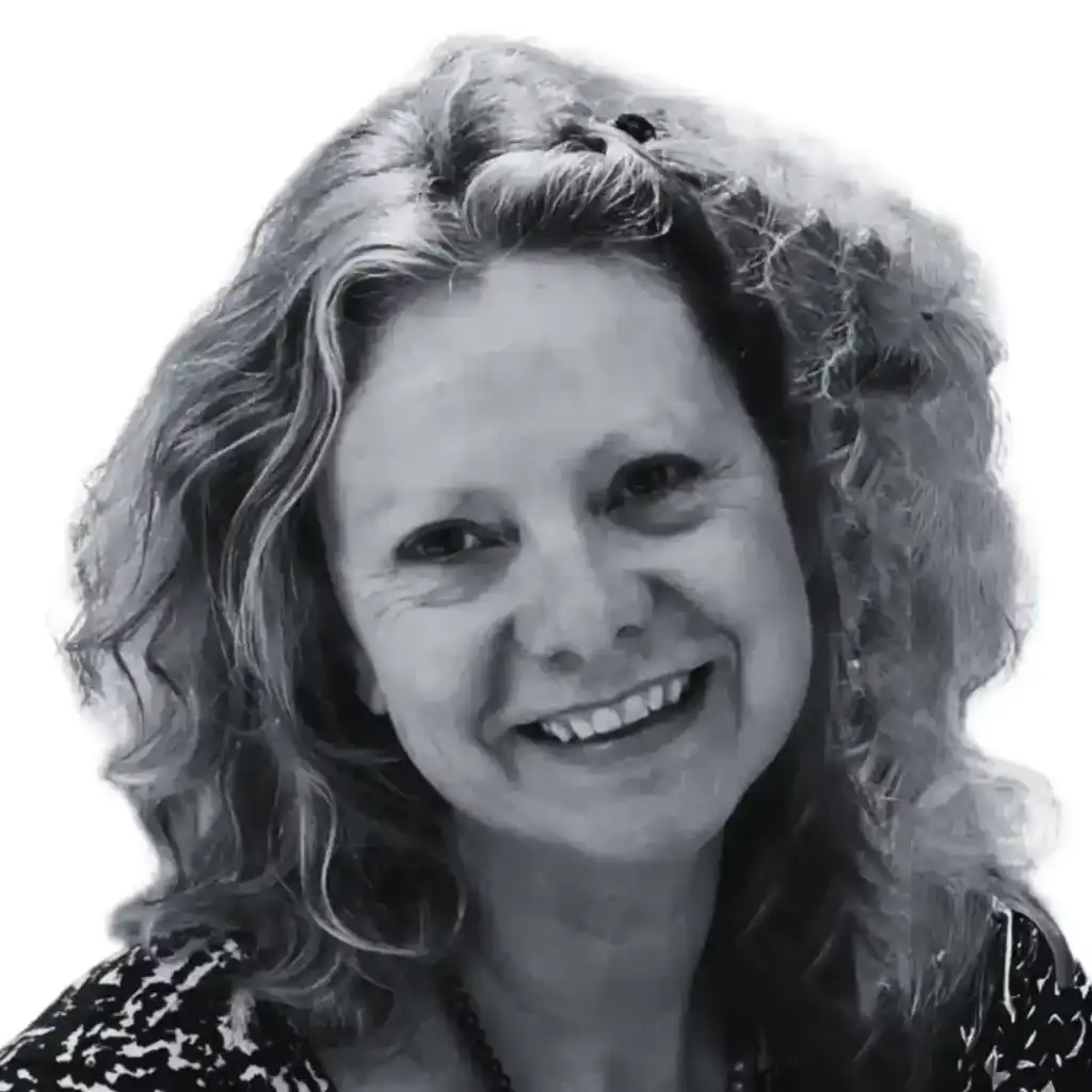 Black and white portrait of a smiling woman with shoulder-length, curly hair. She is wearing a patterned top and a necklace. The background is white, bringing focus to her cheerful expression, reminiscent of the focus required in effective website design service. Opdee Digital Marketing