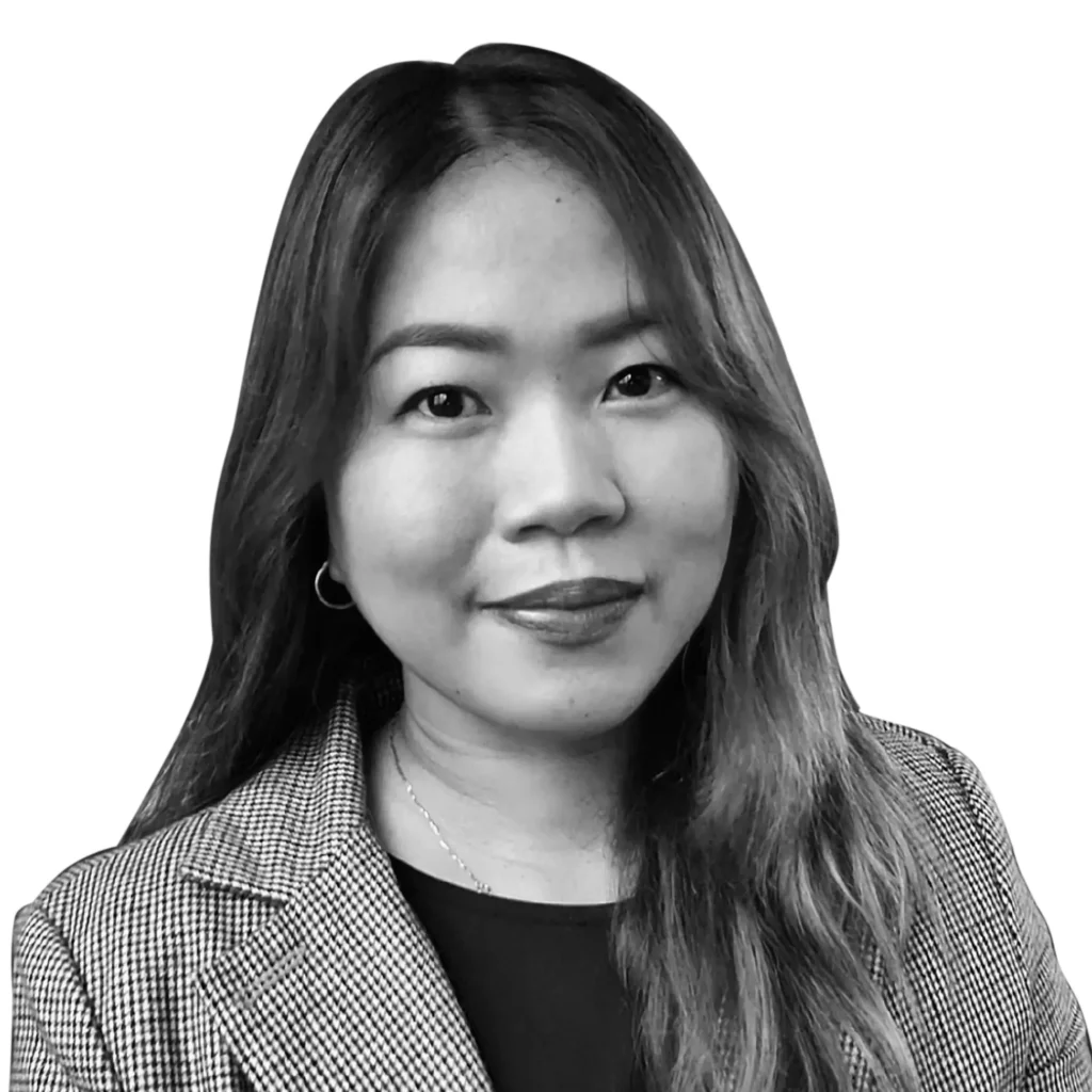Black and white headshot of a woman with long, straight hair. She is smiling slightly, dressed in a blazer over a top, with small hoop earrings. The background is white—a perfect introduction to our process and who we are about us. Opdee Digital Marketing