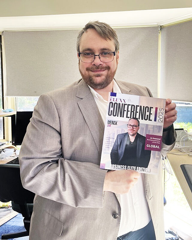 A man in a light suit and glasses stands indoors, smiling and holding a business magazine titled "Conference 2025" featuring his photo on the cover. Office equipment and windows are visible in the background. Opdee Digital Marketing